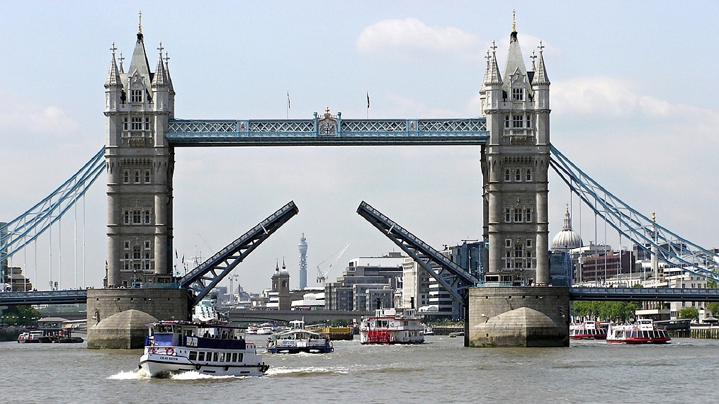Tower Bridge, zvedací most nad řekou Temží. Vedle stojí Tower of London, pevnost jejího Veličenstva.